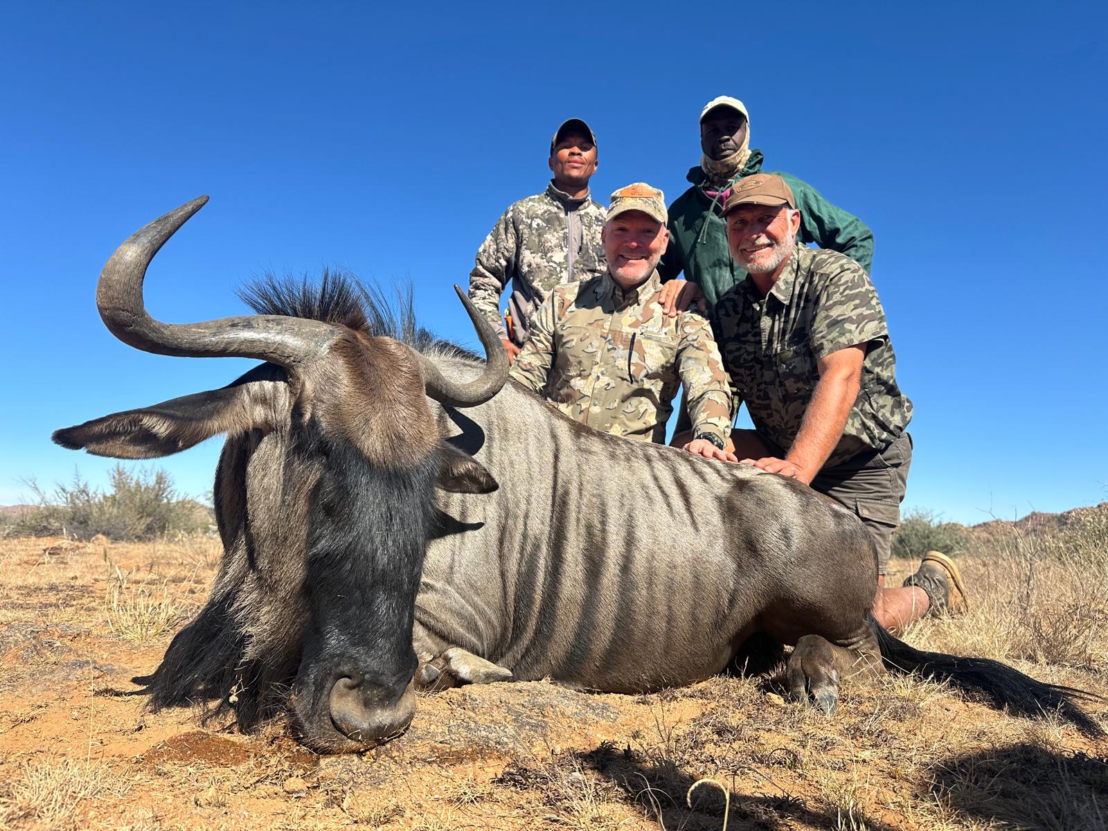 Hunters and local guides gathered behind a harvested wildebeest