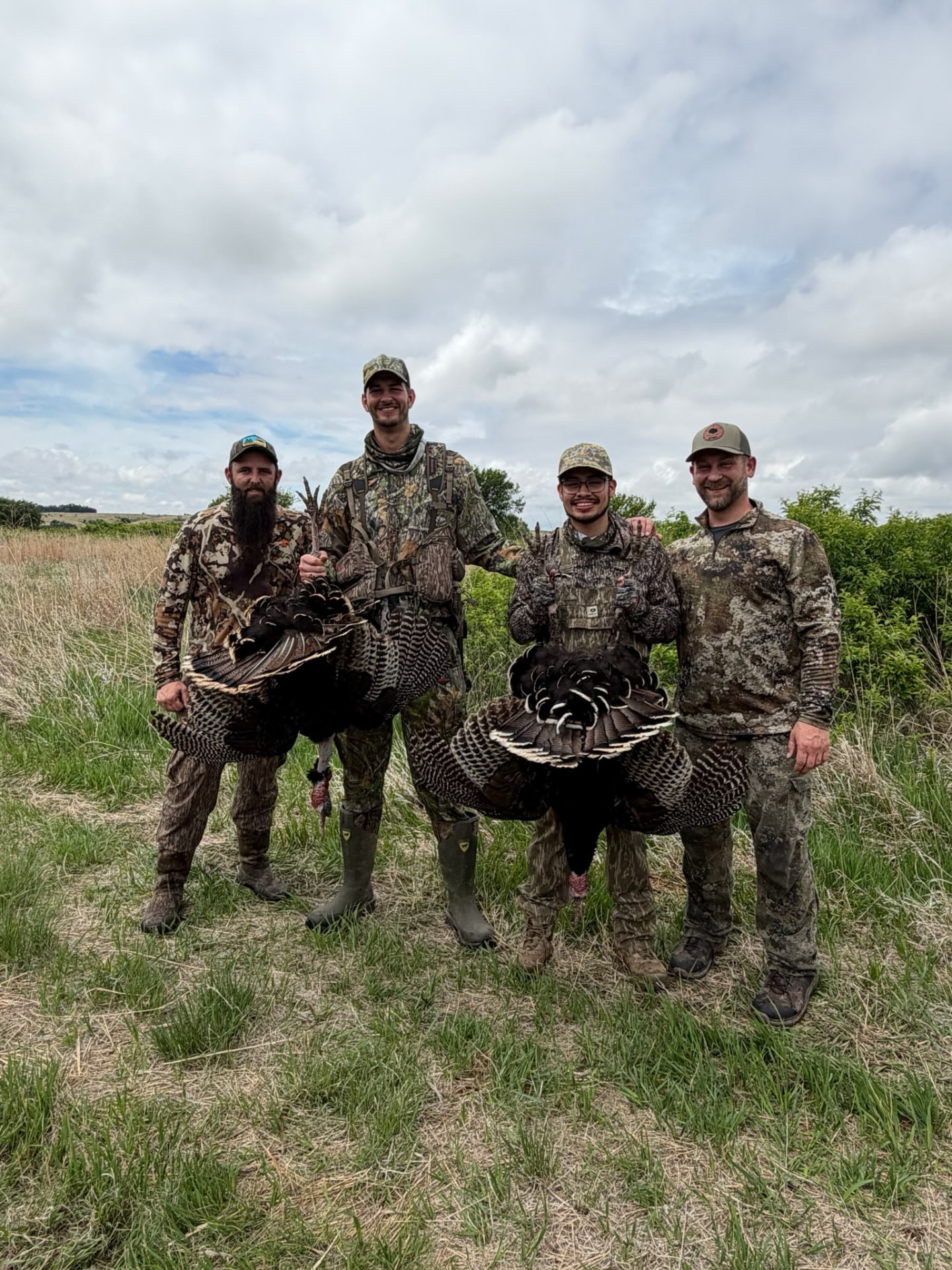 Four men in hunting gear standing together in a field after a morning turkey hunt