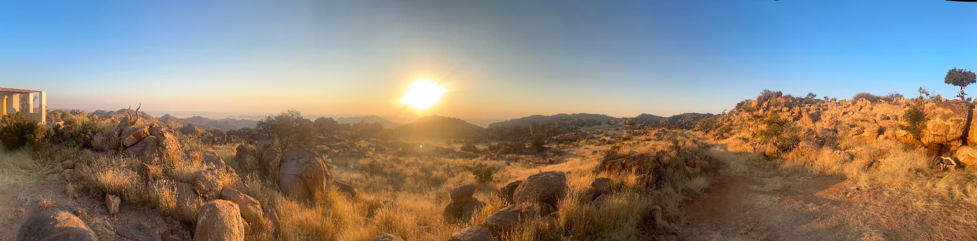 Wide view of dry grass and granite boulders under early morning light